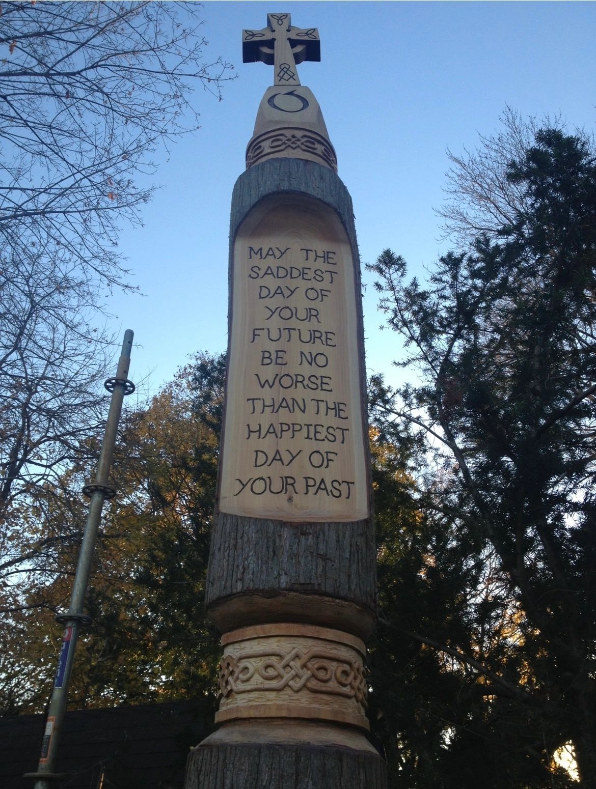 Tall tree trunk carved with a Celtic cross and an Irish blessing