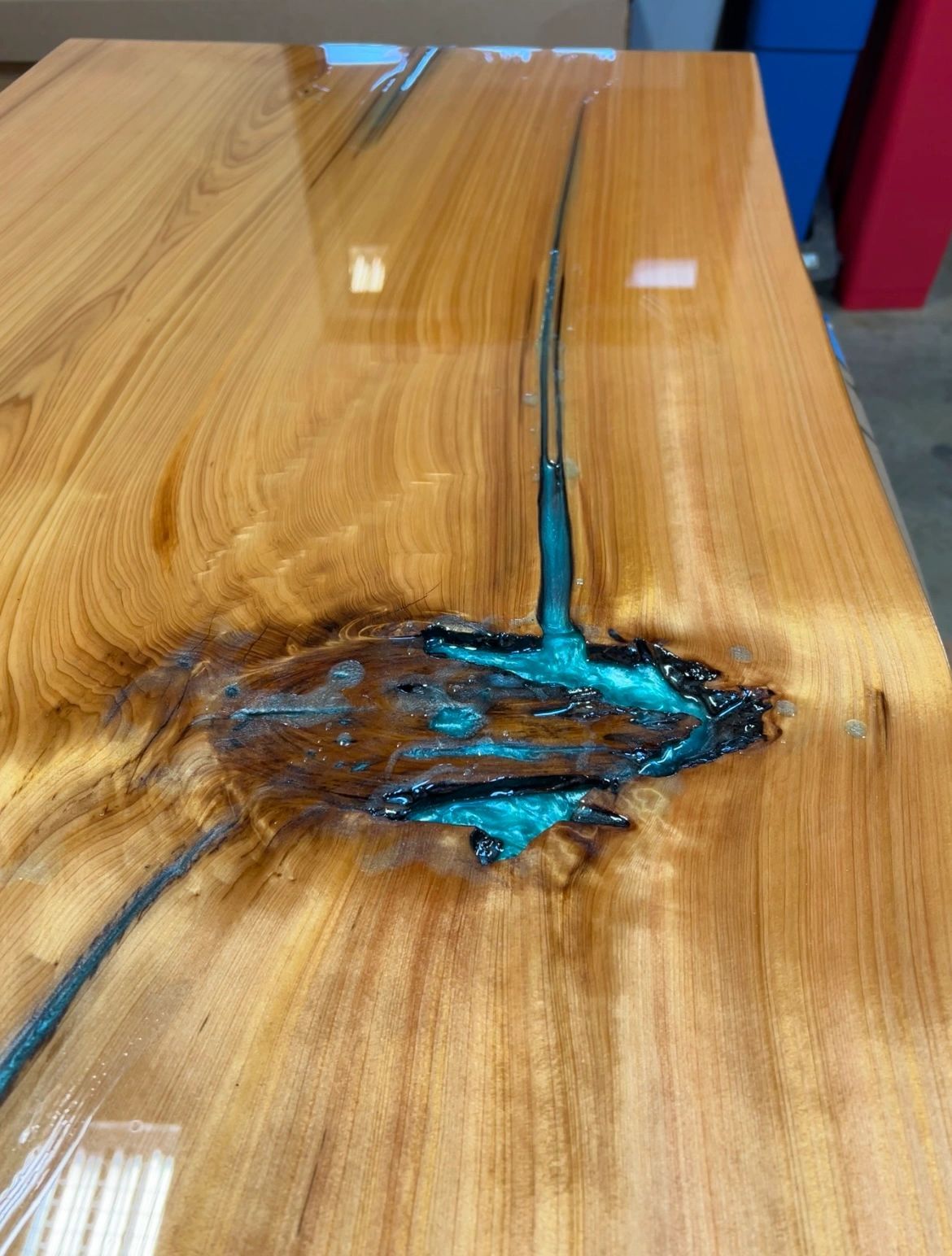Close-up of turquoise resin filling a natural crack in a cypress tabletop