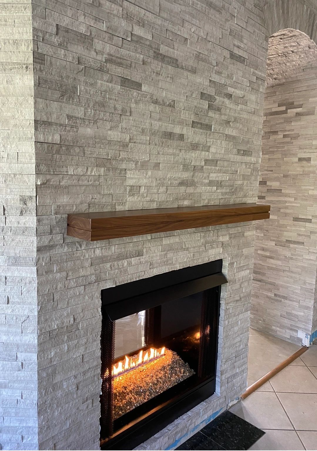 Box mantel on stone. A walnut box mantel on a stacked-stone see-through fireplace.