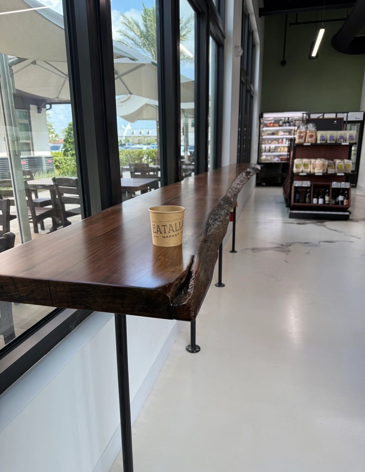 Long live-edge window bar counter on black pipe legs in a commercial space